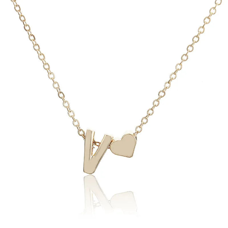 Golden peach heart shaped alloy necklace pendant with a letter design on a white background.