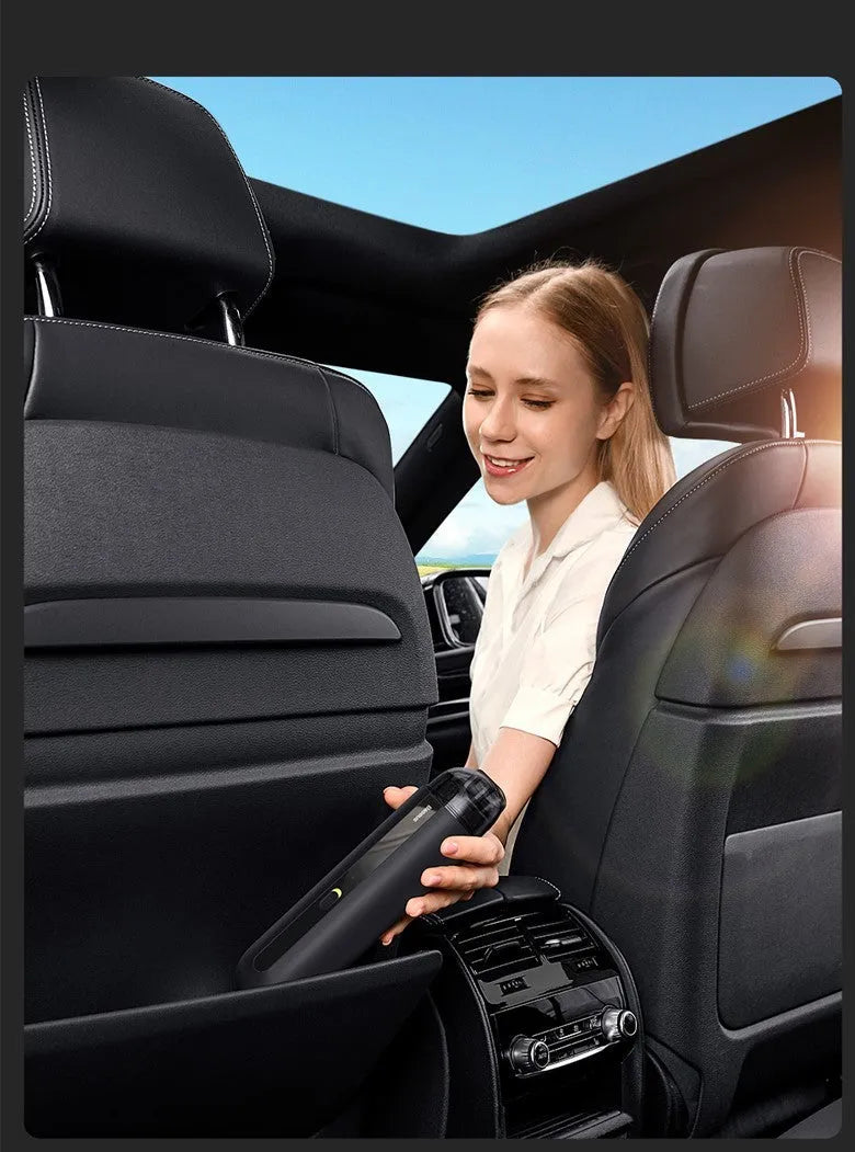 Black cordless handheld car vacuum cleaner with blowing hose attachment on a desktop.