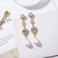Gold pearl drop earrings with heart-shaped alloy frame and single pearl pendant on gold-tone finish