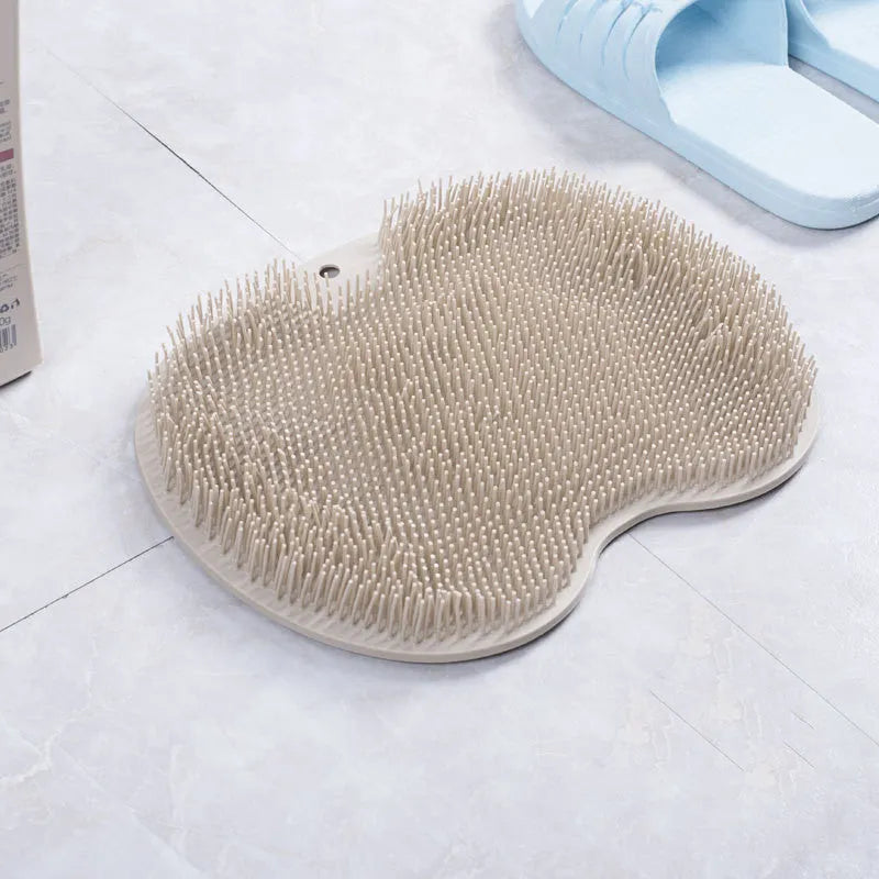 Orange TPR bath brush with silicone bristles and suction cups on base, shown on bathroom tiles.