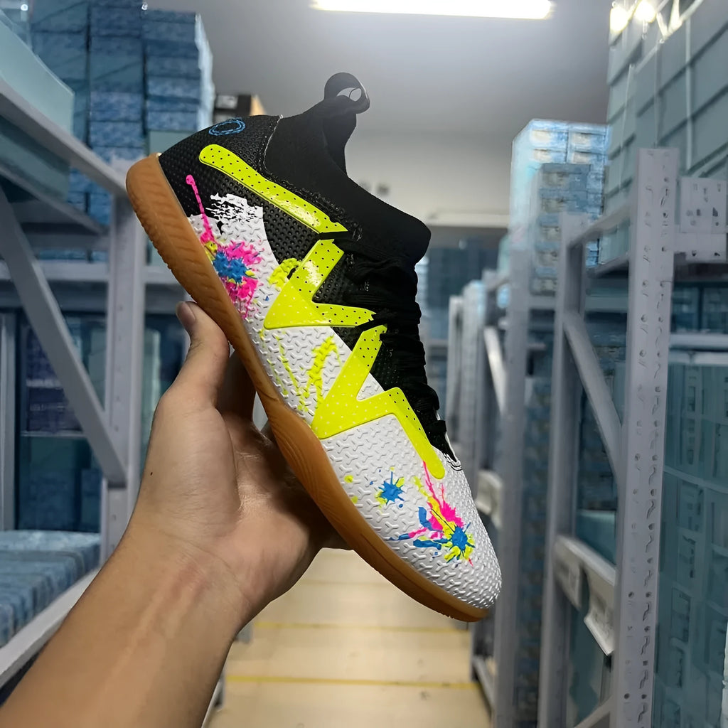 Low-top black and yellow football trainers with removable screw-in studs on the sole.