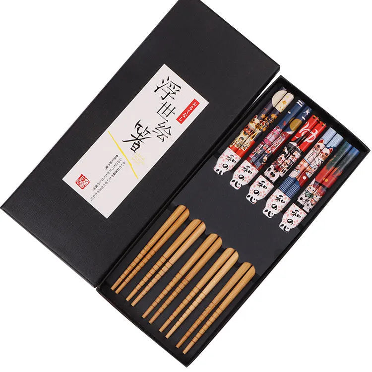 Set of five pairs of bamboo chopsticks with Japanese lucky cat and elegant blue patterns on a table.
