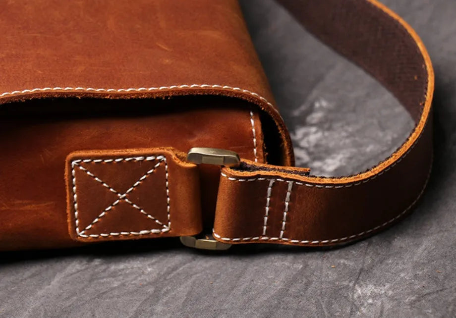 Men's vintage brown leather messenger bag with adjustable strap, shown open to reveal internal organiser pockets.