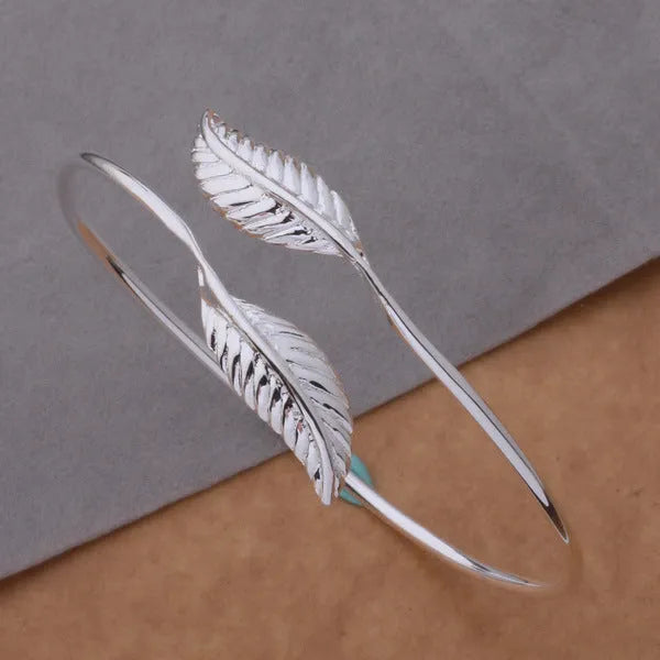 Silver metal bangle bracelet with open cuff design, 6.3cm diameter, on white background