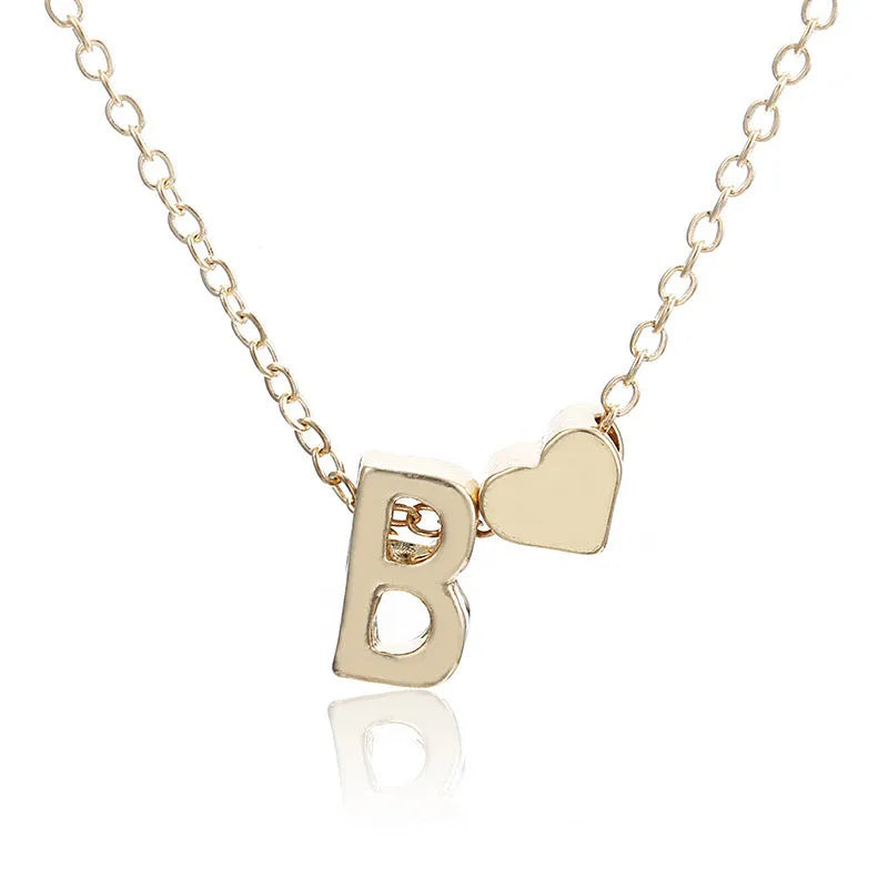 Golden peach heart shaped alloy necklace pendant with a letter design on a white background.