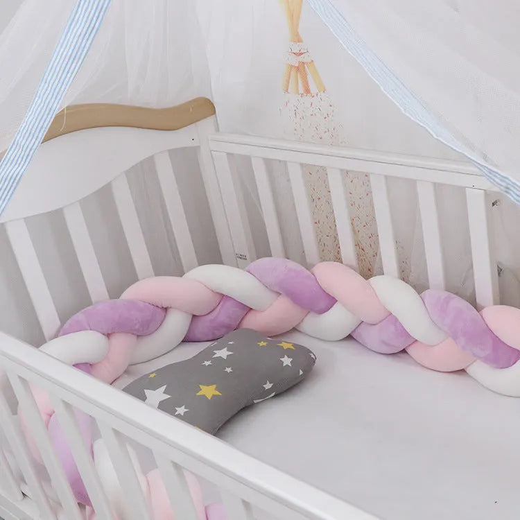 Braided knot crib bumper in spandex velvet, shown bending to fit a white wooden cot.