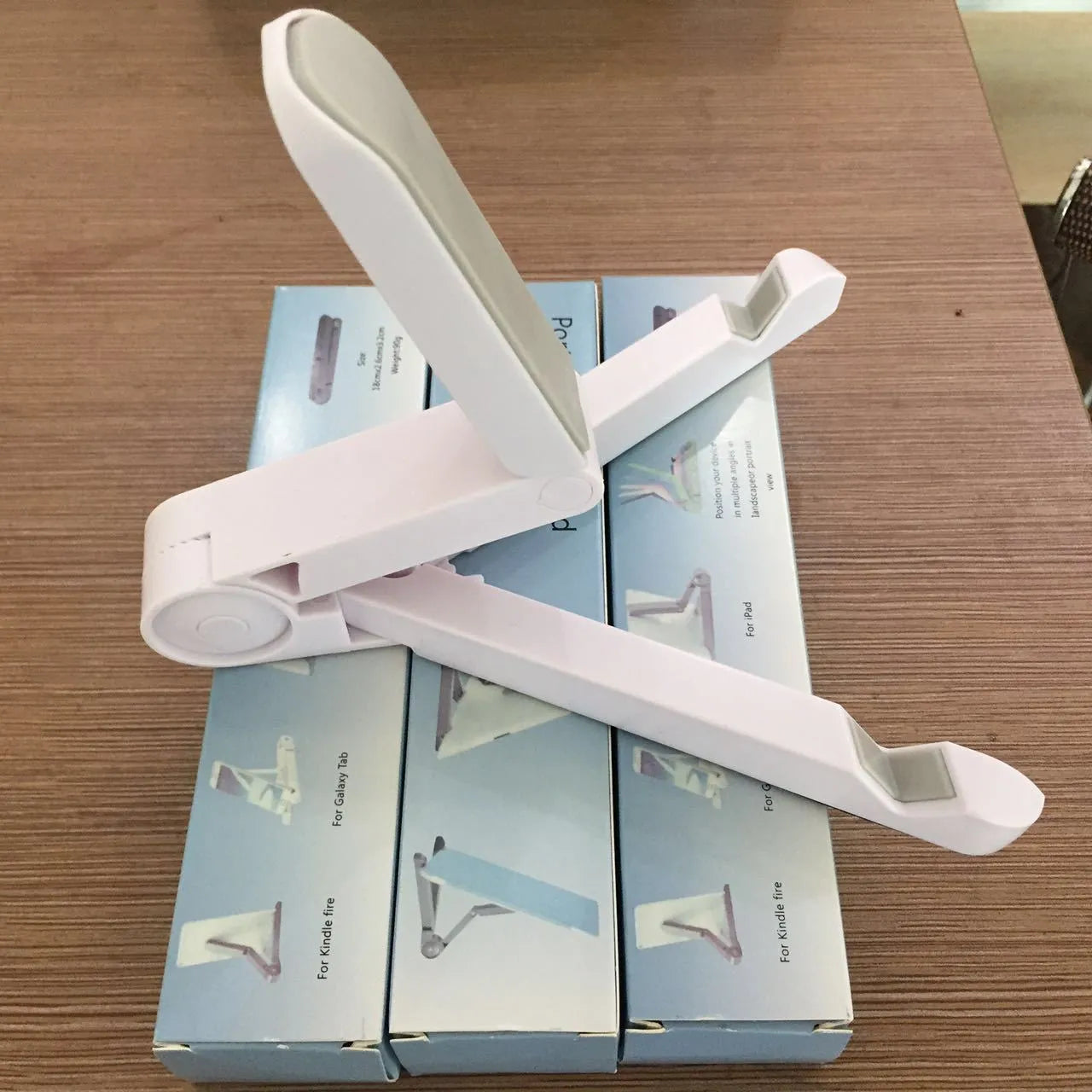 Foldable tablet holder shown in black with smartphone mounted in landscape orientation
