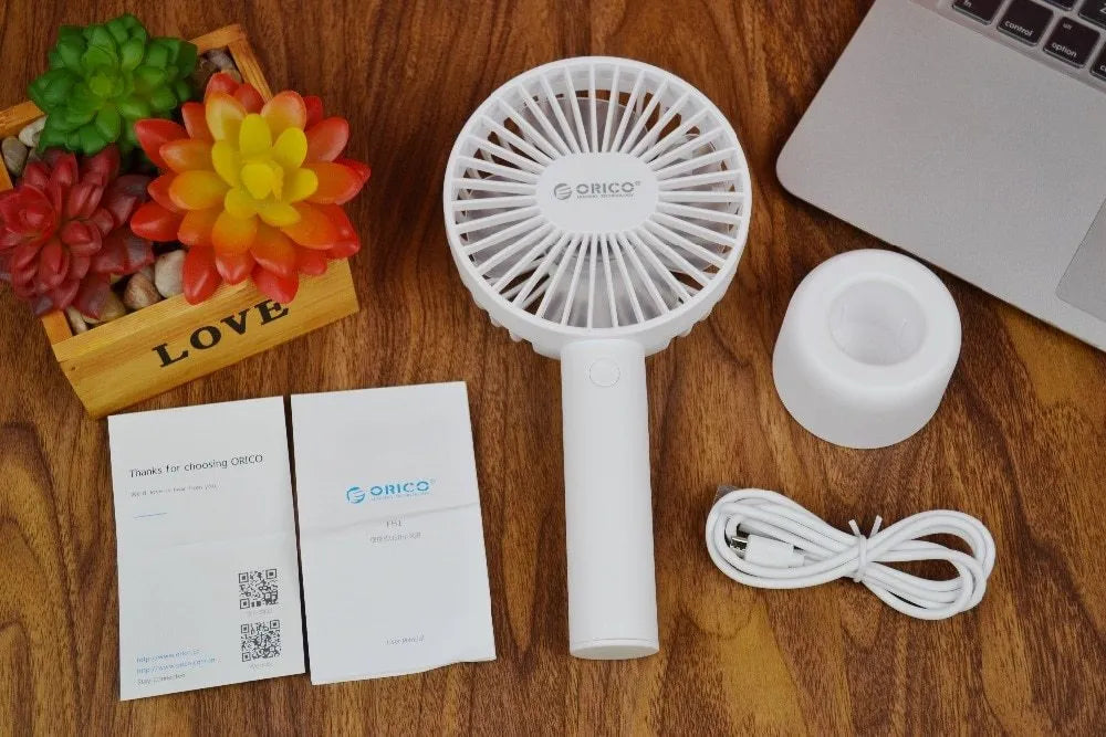 White ORICO FH1 handheld USB rechargeable desk fan with three-speed control on a desk.