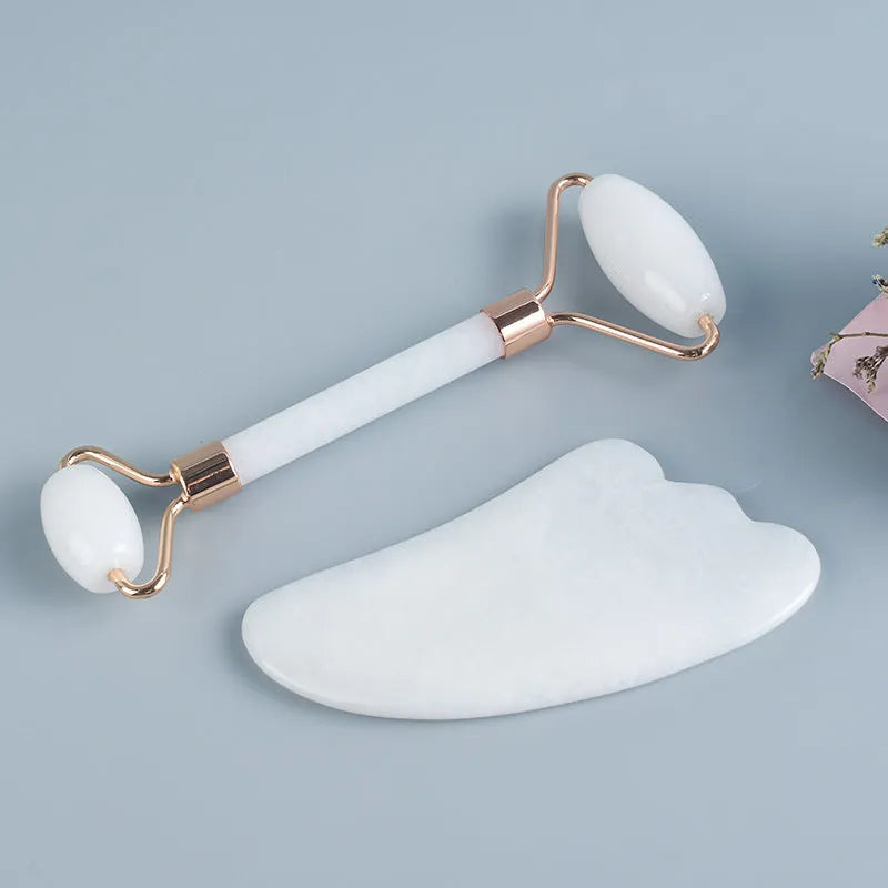 Natural white jade double-headed facial roller and gua sha scraping board set on a plain background.