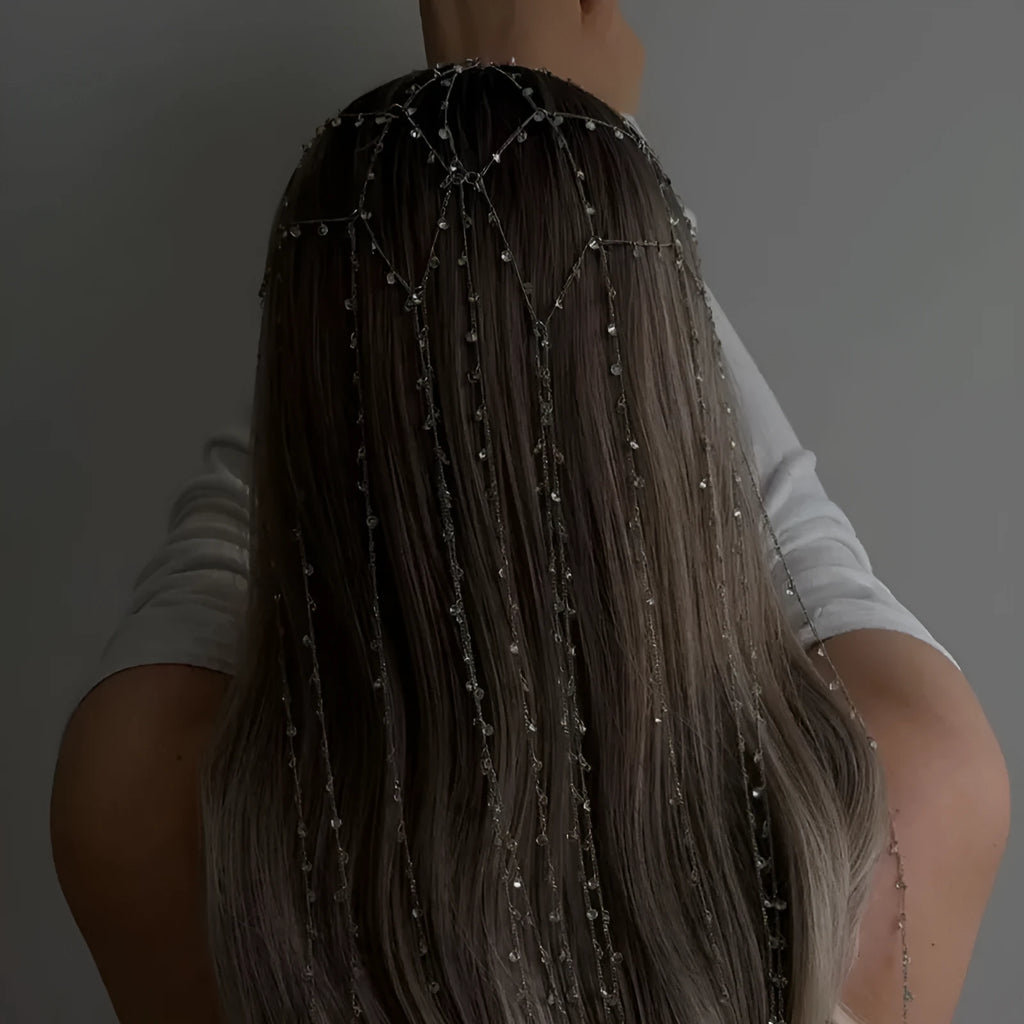 Gold rhinestone and mesh hairband with a long tassel, laid flat on a dark surface.
