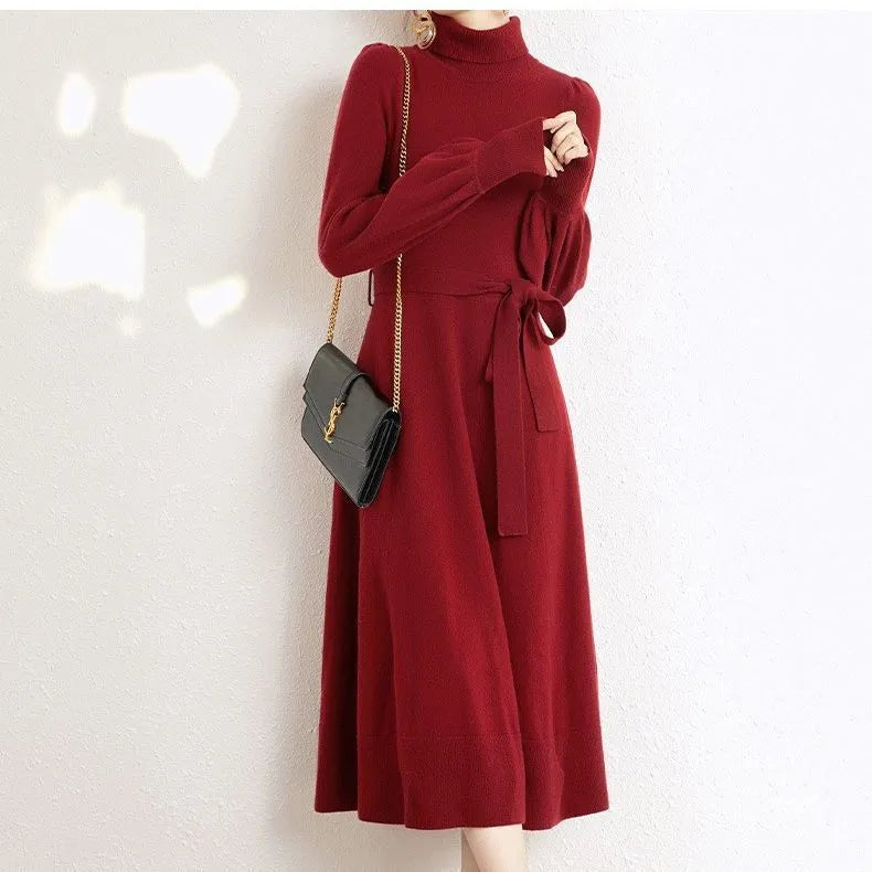A rose red turtleneck knit dress with long sleeves, an elastic waist, and a loose mid-length skirt on a hanger.