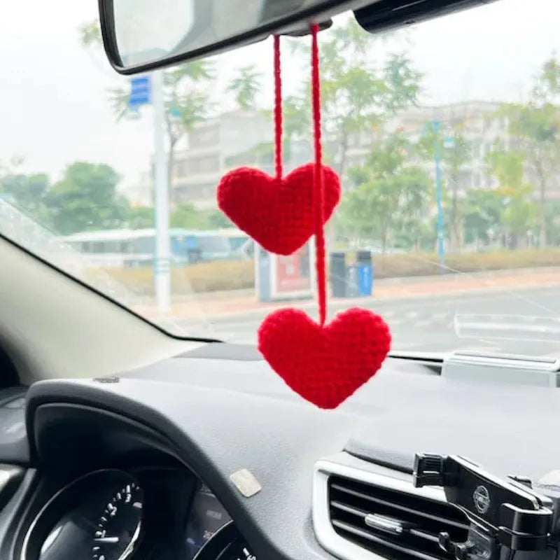 Green and white knitted wool car plant decoration with macramé texture and a white hanging rope.