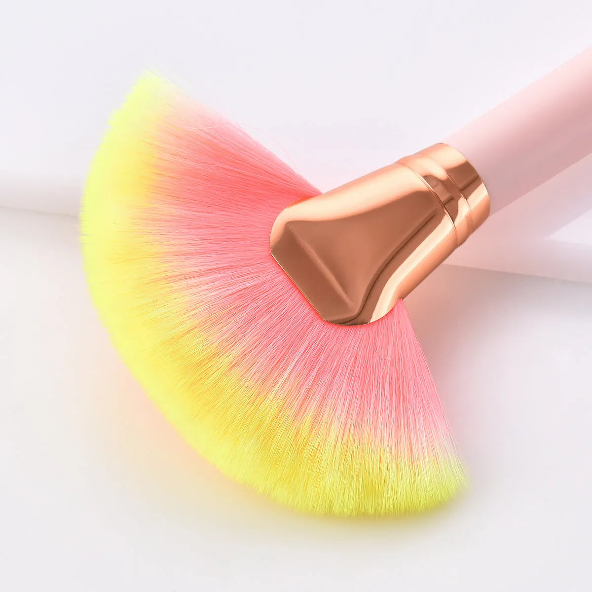 Twelve pink makeup brushes with nylon bristles and wood handles laid out in a row on a light background