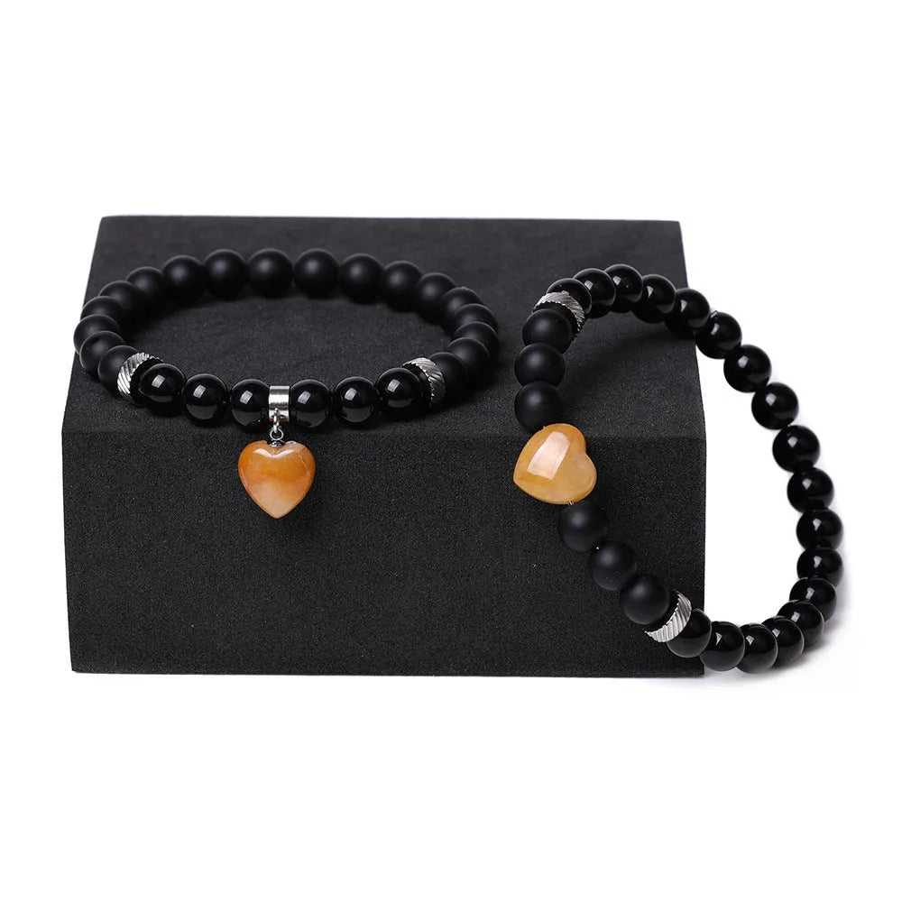 A pair of matching bracelets with polished geometric heart pendants made from natural stone.