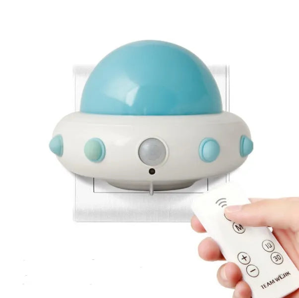 Blue UFO-shaped bedside night light with remote control on a wooden table.