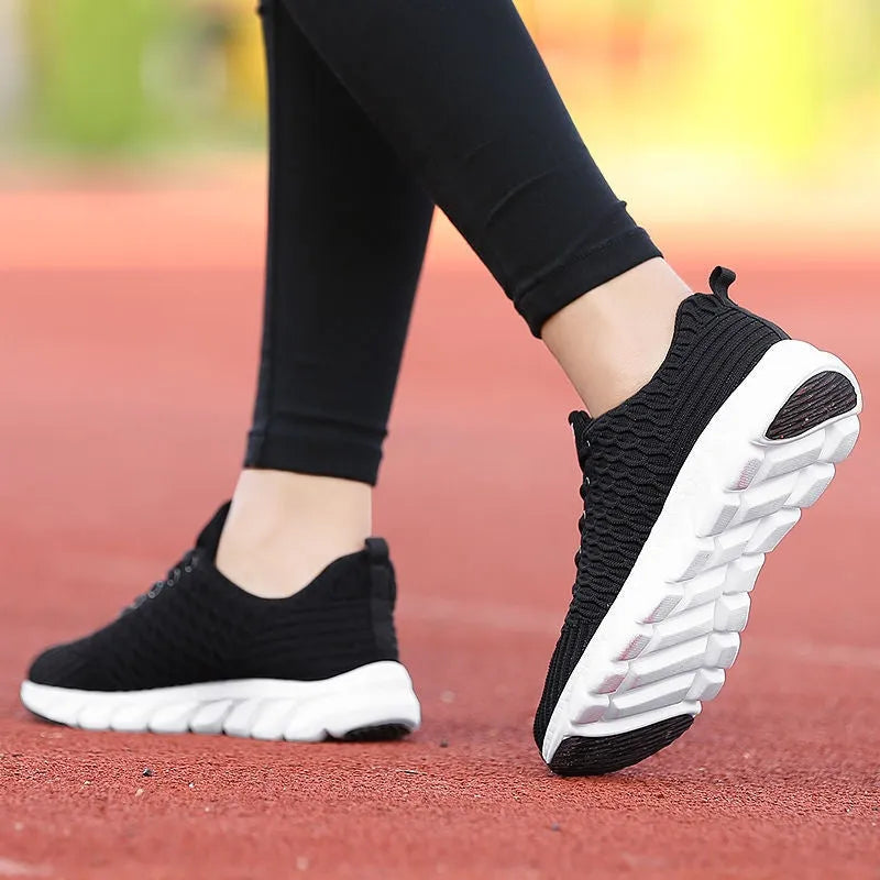 Women's black running shoe with fly weave upper and textured wear-resistant outsole.