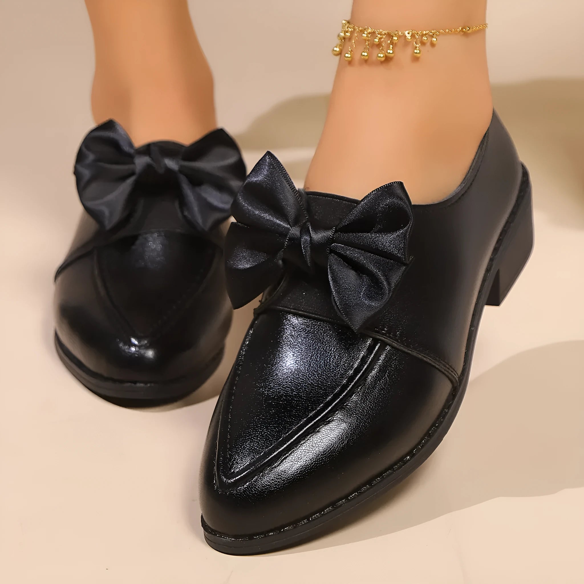 Women's beige loafers with a large decorative bow, showcasing rounded toe and slip-on design.