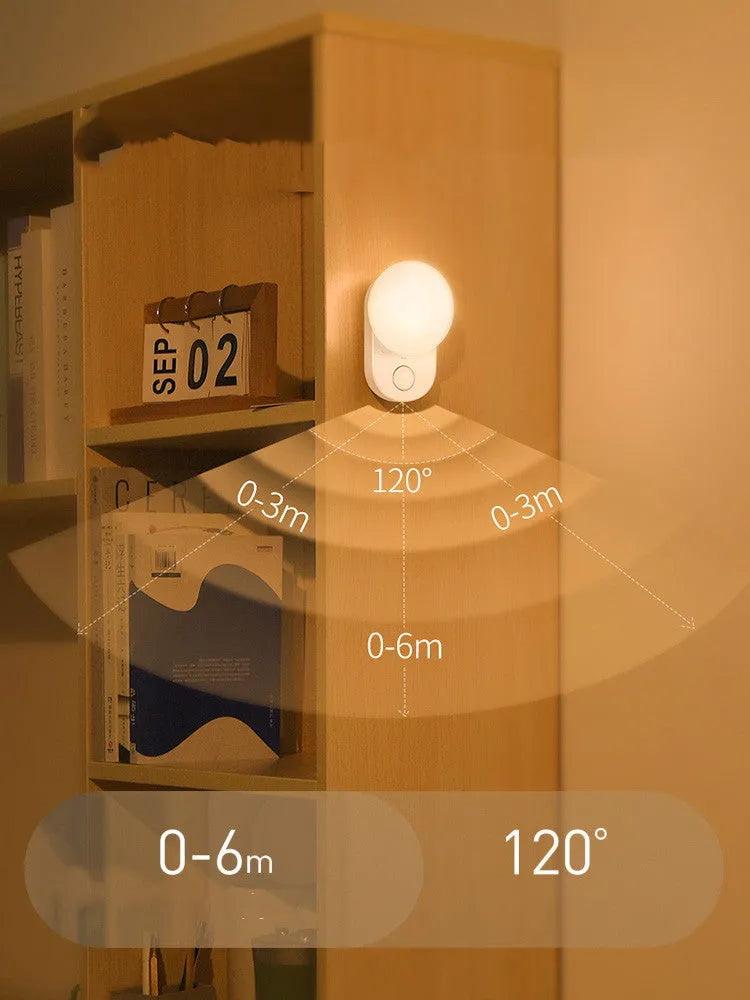 White Baseus rechargeable sensor night light with LED glow on a bedside table.