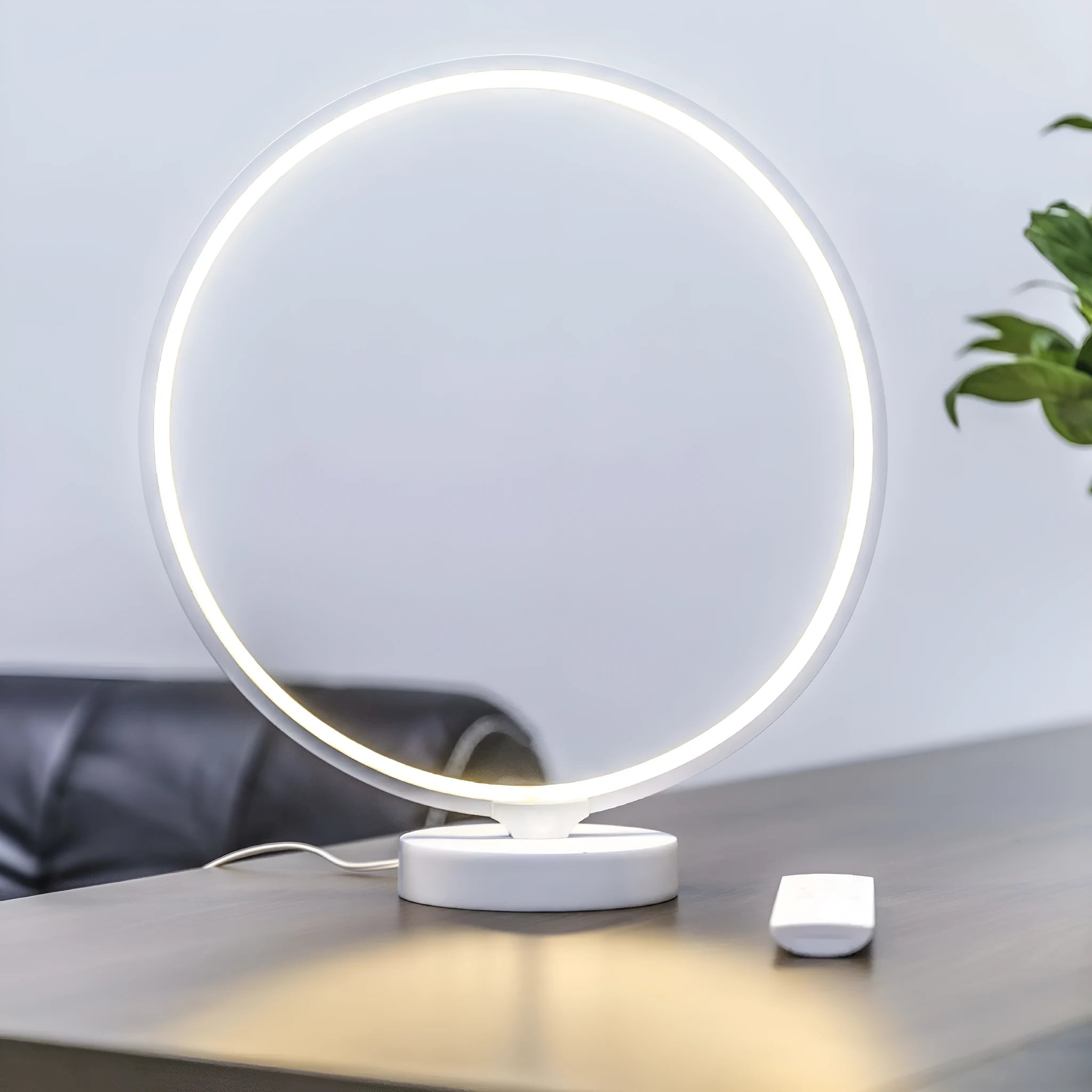 White Full Moon Lamp table light with remote control on a wooden surface.