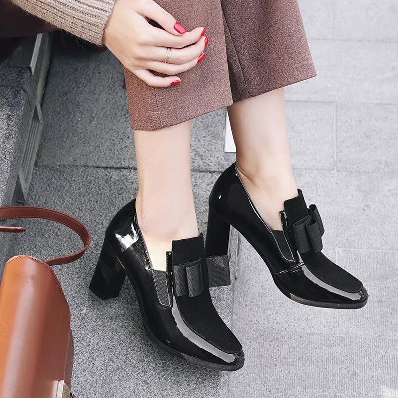 Black patent leather women's high heels with a thick chunky heel and square toe on a rubber sole.
