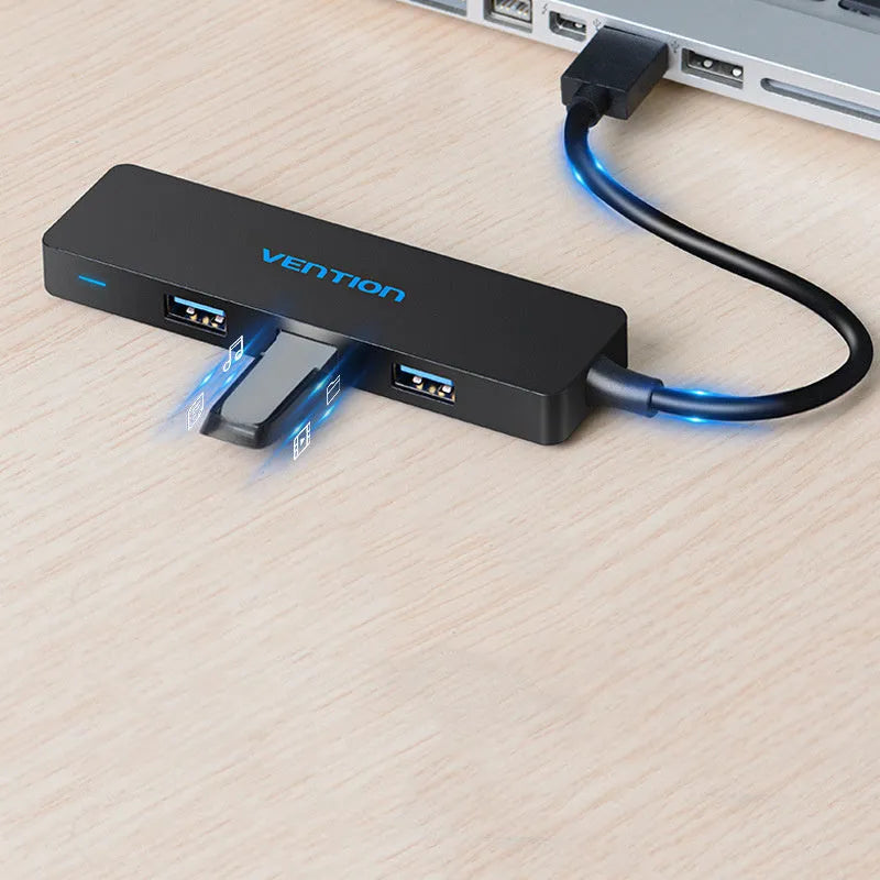 Black four-port USB 3.0 hub with a short cable next to a laptop