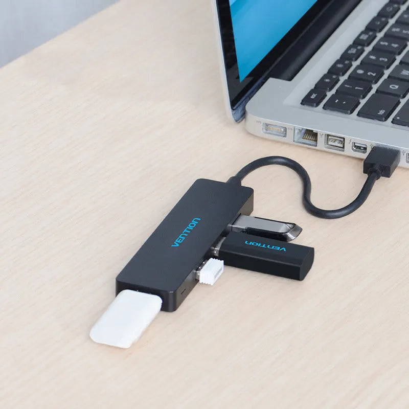 Black four-port USB 3.0 hub with a short cable next to a laptop