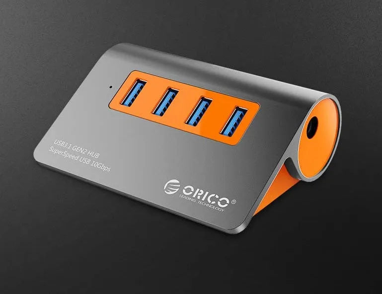 Dark grey USB hub with four ports and orange accents, showing aluminium construction and separate data cable