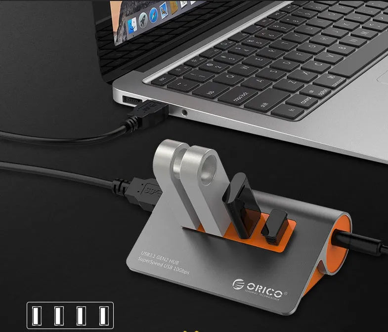 Dark grey USB hub with four ports and orange accents, showing aluminium construction and separate data cable