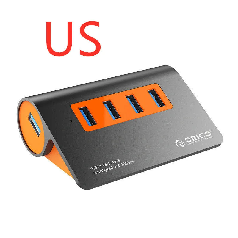 Dark grey USB hub with four ports and orange accents, showing aluminium construction and separate data cable