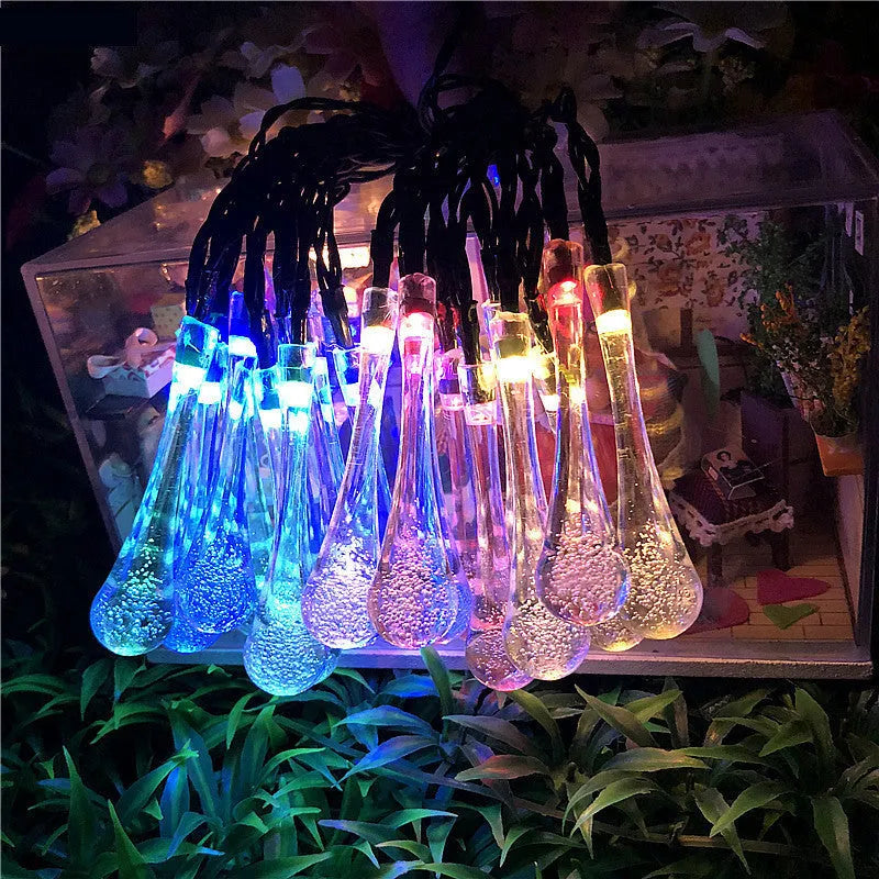 Solar-powered outdoor string lights with water drop shaped pendants on a 6.5 metre cable, shown with solar panel and ground spike.
