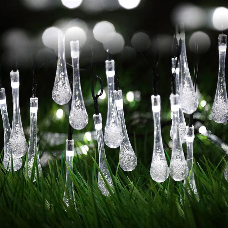 Solar-powered outdoor string lights with water drop shaped pendants on a 6.5 metre cable, shown with solar panel and ground spike.