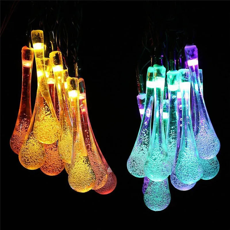 Solar-powered outdoor string lights with water drop shaped pendants on a 6.5 metre cable, shown with solar panel and ground spike.
