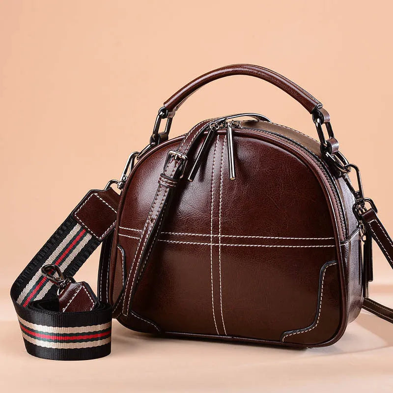 Round leather handbag with zippered closure and double soft handles in wine red colour