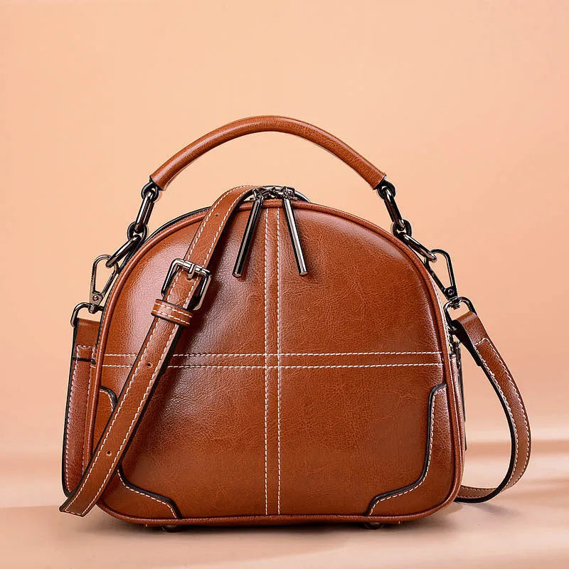 Round leather handbag with zippered closure and double soft handles in wine red colour
