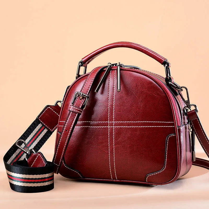 Round leather handbag with zippered closure and double soft handles in wine red colour