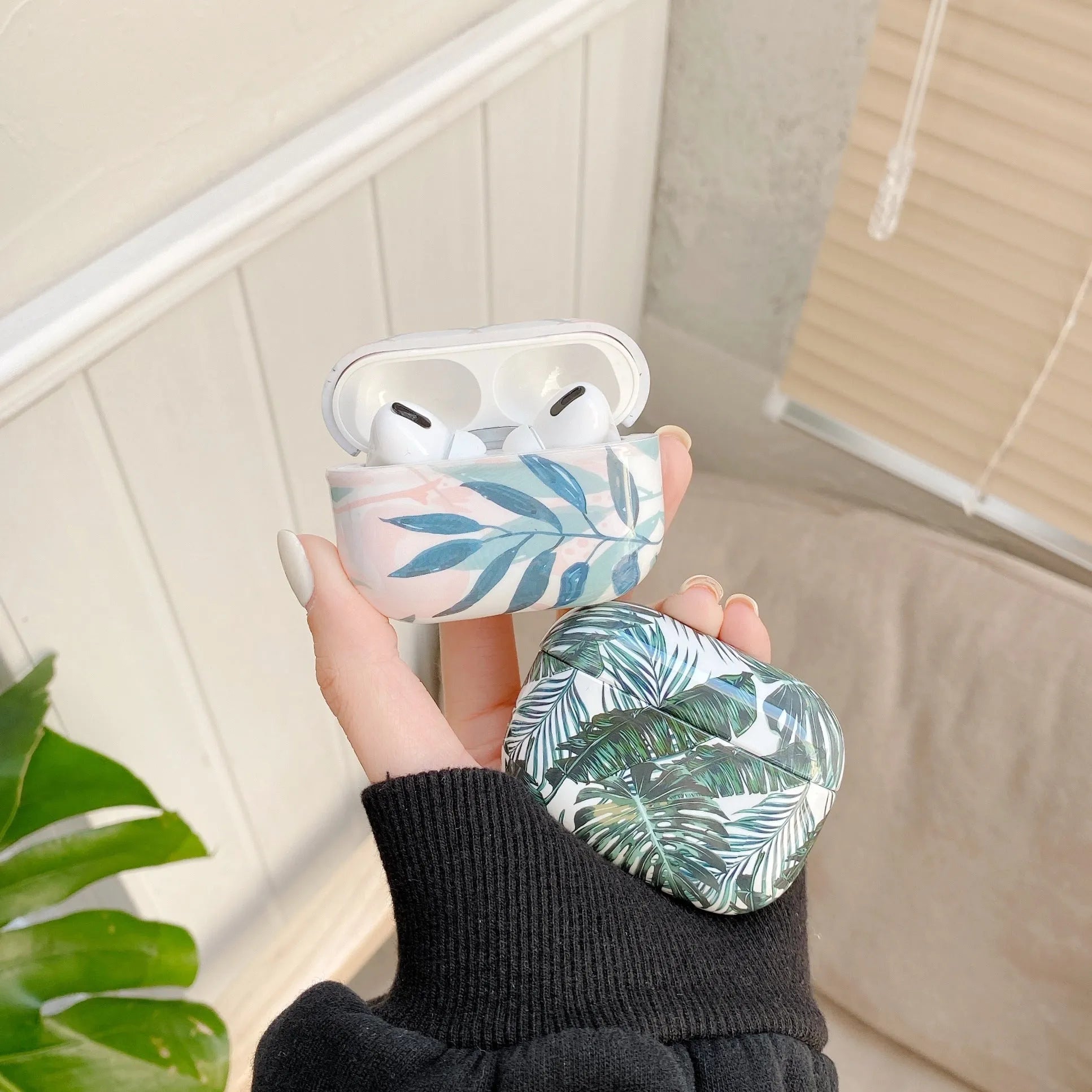 Blue and green soft TPU AirPods cases featuring a painted tropical banana leaves pattern.