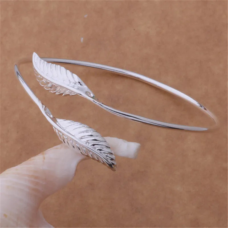 Silver metal bangle bracelet with open cuff design, 6.3cm diameter, on white background