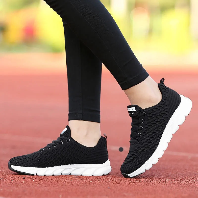 Women's black running shoe with fly weave upper and textured wear-resistant outsole.