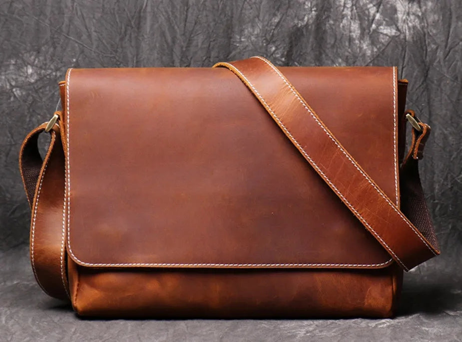 Men's vintage brown leather messenger bag with adjustable strap, shown open to reveal internal organiser pockets.