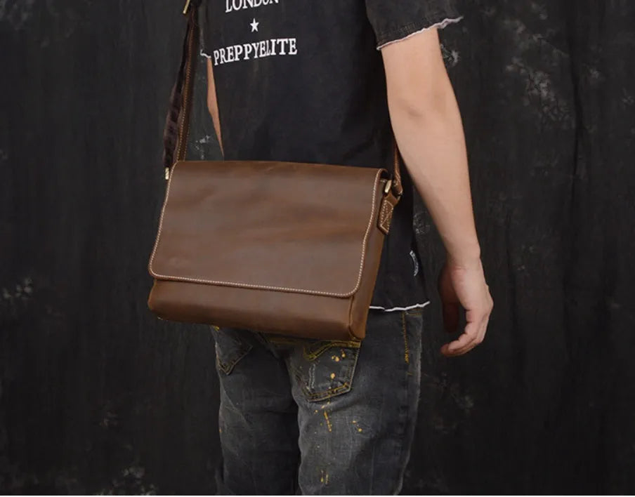 Men's vintage brown leather messenger bag with adjustable strap, shown open to reveal internal organiser pockets.