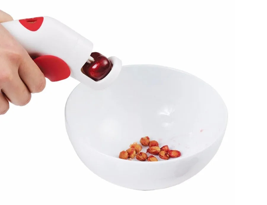 Close-up of a handheld cherry pitter with a plastic handle and stainless steel pitting mechanism