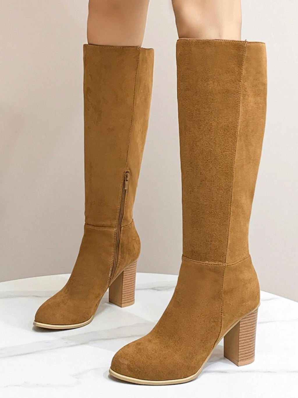 Black square toe high heel fashion boots for women on a plain background.