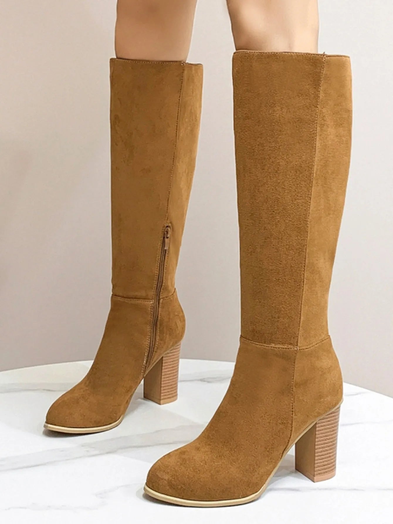Black square toe high heel fashion boots for women on a plain background.