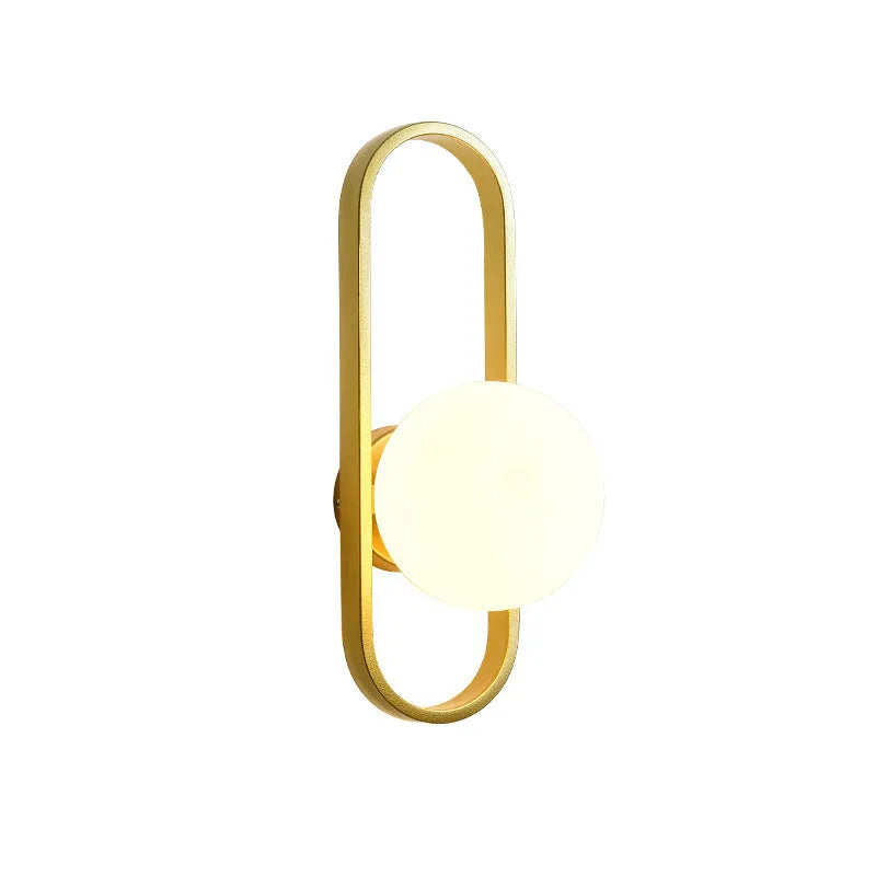 Minimalist modern wall lamp with a clear glass shade on an iron body, shown in a black finish mounted on a wall.