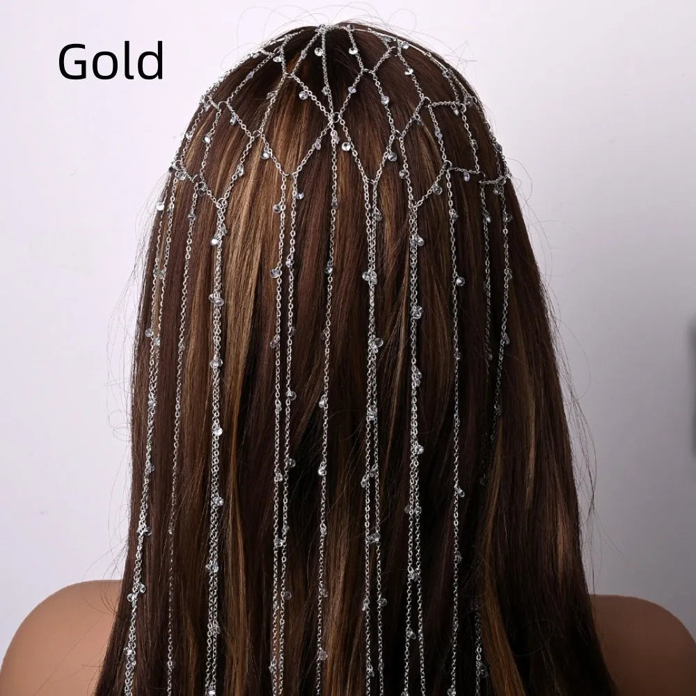 Gold rhinestone and mesh hairband with a long tassel, laid flat on a dark surface.