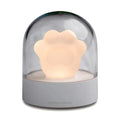 Grey or pink cat paw shaped USB rechargeable night light and music box on a desktop.