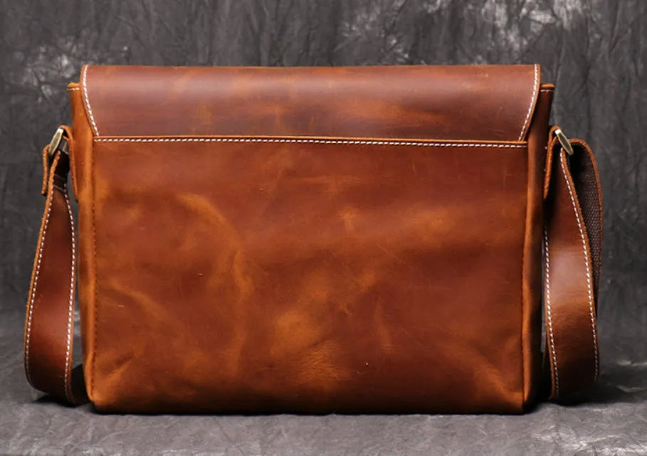Men's vintage brown leather messenger bag with adjustable strap, shown open to reveal internal organiser pockets.