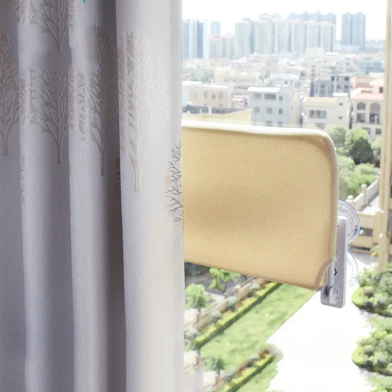 Cat resting on a suction cup window hammock made of plush fabric and steel in beige colour