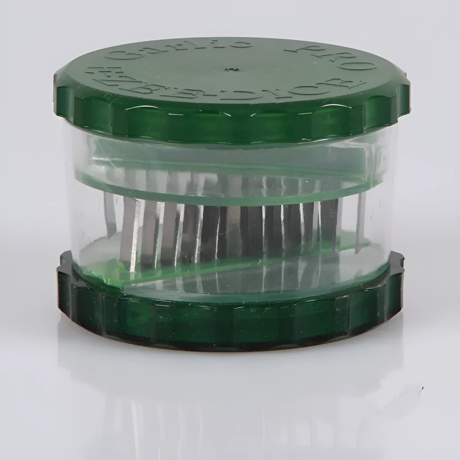 Green transparent PP garlic peeler measuring 8.5 by 8.5 by 6 cm used to peel and crush garlic cloves in a kitchen setting.