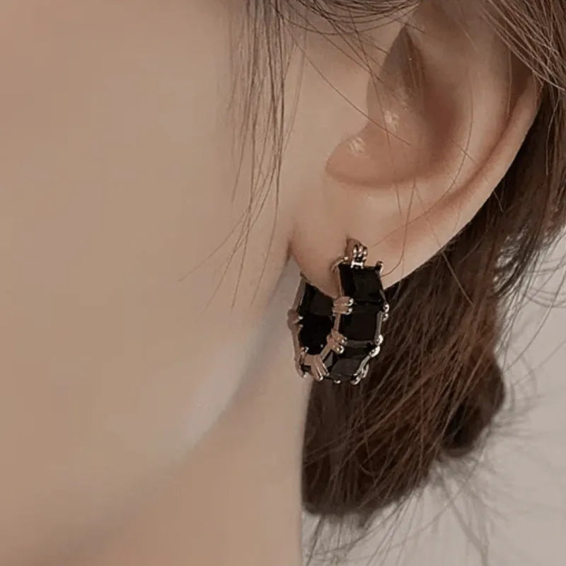 Geometric U-shaped gold-tone earrings with black zircon stones, approximately 20mm diameter